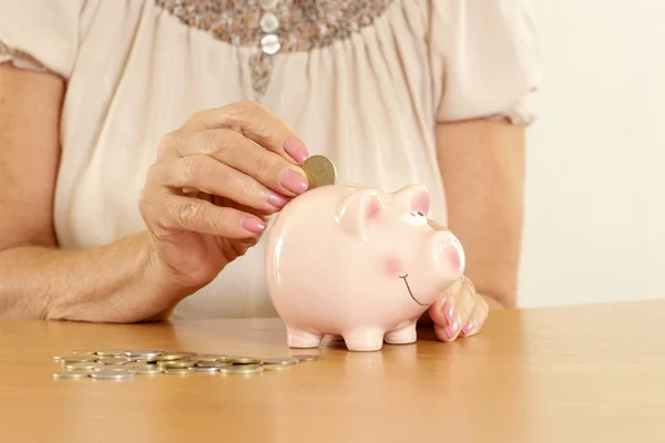 Piggy bank and hand with coin — Stock Photo, Image