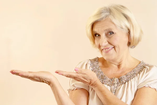 Agradable mujer mayor sobre un fondo beige —  Fotos de Stock