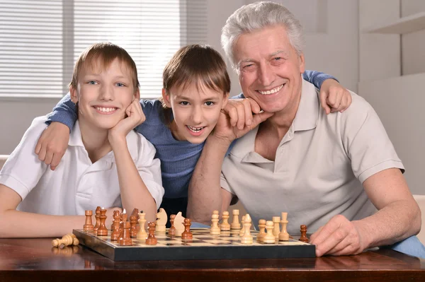 Два мальчика и дедушка играют в шахматы — стоковое фото