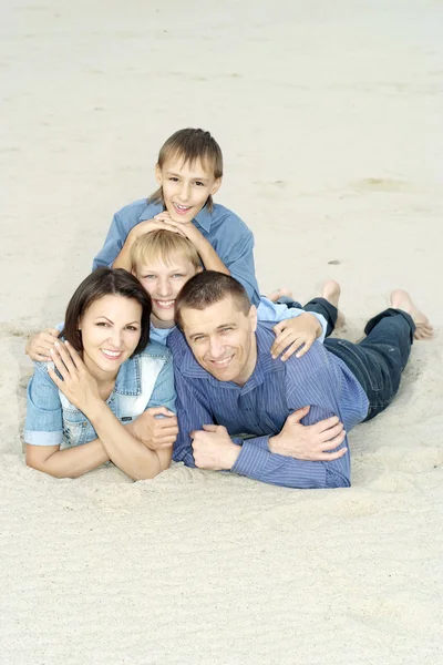 Семья, лежащая на песке — стоковое фото