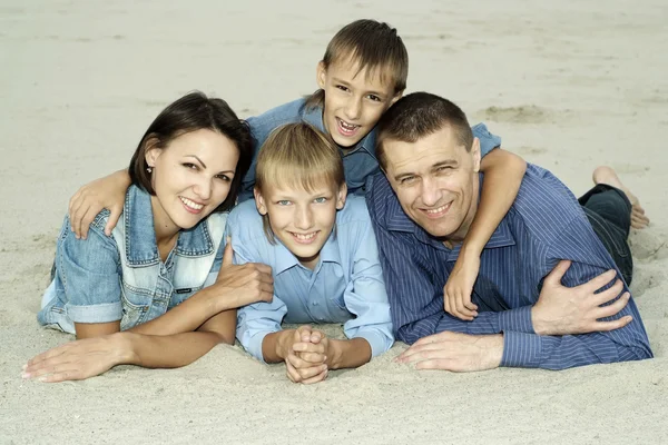 Familie liegt im Sand — Stockfoto