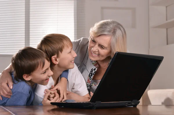 Dois meninos e avó com um laptop — Fotografia de Stock