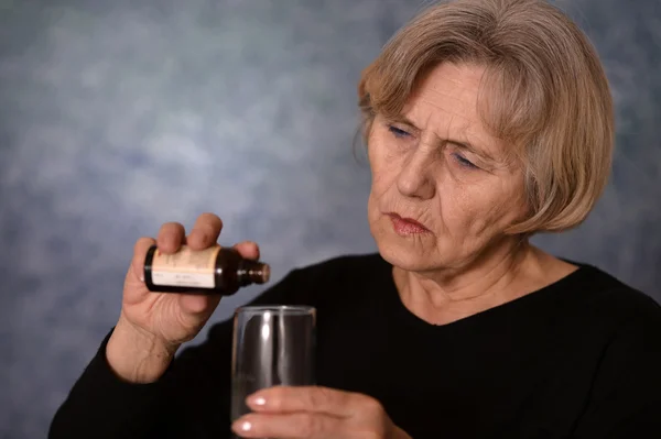 Пожилая кавказская женщина лечится лекарствами на сером фоне — стоковое фото