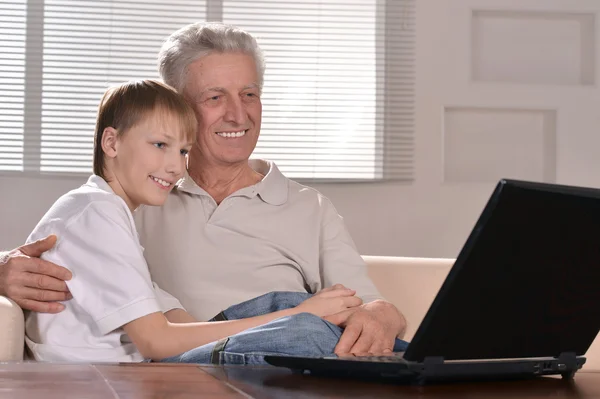 Pojken och hans farfar med en bärbar dator — Stockfoto