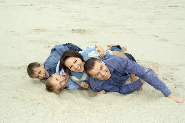 Família deitada na areia — Fotografia de Stock
