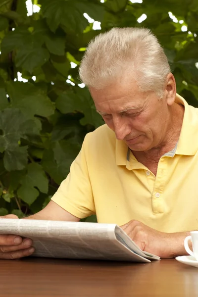 Διαβάζοντας την εφημερίδα παλαιότερη άνθρωπος που κάθεται στη βεράντα — Φωτογραφία Αρχείου