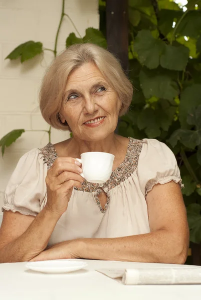 Lachende oudere vrouw die zit op de veranda — Stockfoto