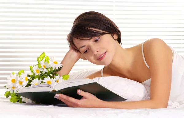 Woman reading a cake on a bed — Stock Photo, Image