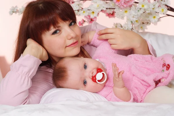 Eine schöne Mutter mit ihrer Tochter im Bett liegend — Stockfoto