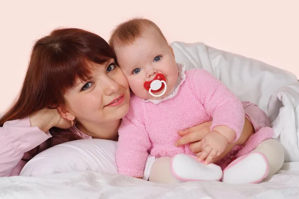 A beautiful good mummy with her daughter lying in bed — Stock Photo, Image