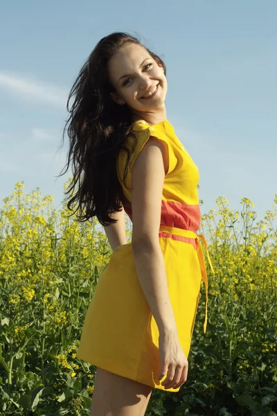 Улыбающаяся молодая женщина посреди желтых цветов — стоковое фото