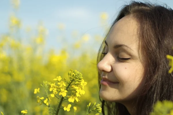 Charmig ung kvinna mitt i gula blommor — Stockfoto