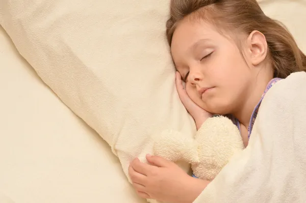 Linda niña durmiendo con un juguete en su cama —  Fotos de Stock