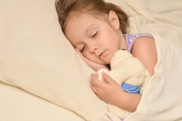 Söt liten flicka sova med en leksak i sin säng — Stockfoto