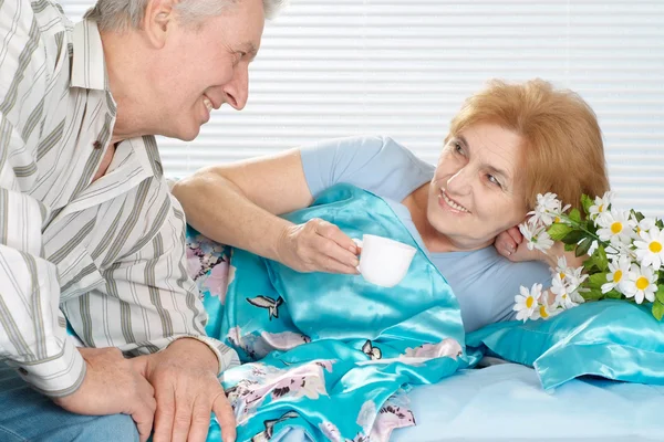 Beautiful older couple resting in the bedroom after a hard working week — Stock Photo, Image
