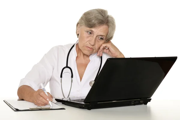 Elderly woman doctor sitting with laptop on white — Stock Photo, Image