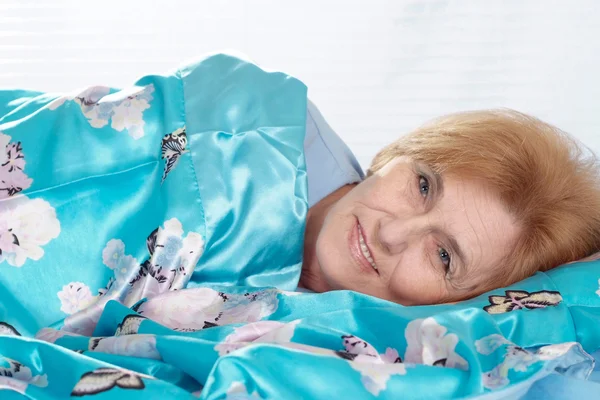 Красивая пожилая женщина отдыхает в спальне после напряженной рабочей недели — стоковое фото