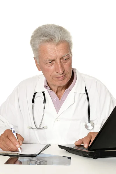 Médico de edad avanzada con un portátil sobre un fondo blanco — Foto de Stock