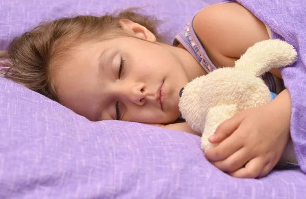 Schattig klein meisje slapen met een stuk speelgoed in haar bed — Stockfoto