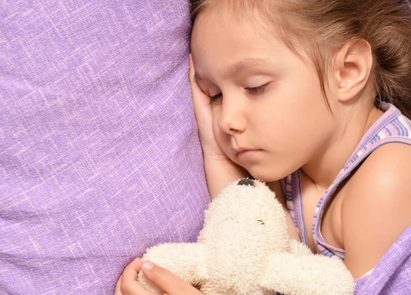 Roztomilá holčička spí s hračkou v posteli — Stock fotografie