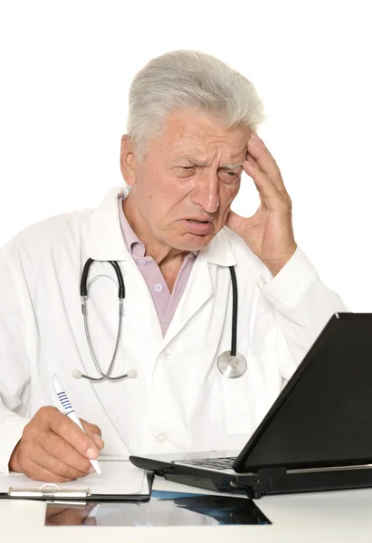 Médico de edad avanzada con una computadora portátil en un blanco — Foto de Stock