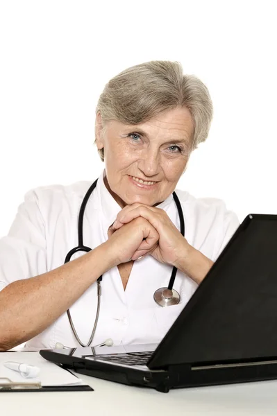 Elderly woman doctor sitting with laptop on white — Stock Photo, Image