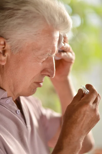 Elderly man holding a thermometer at home — Stock Photo, Image