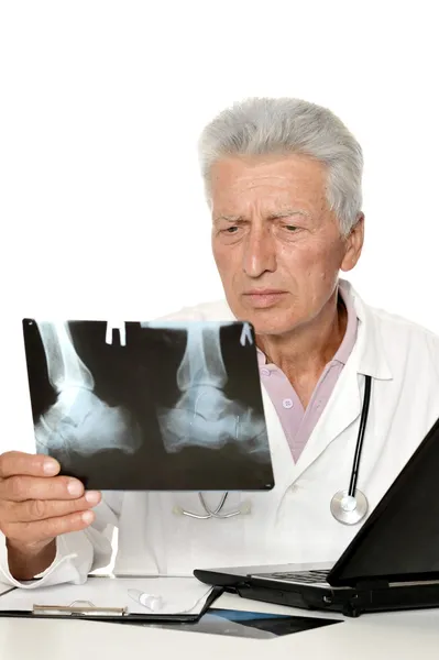 Old doctor looking x-rays on a white background — Stock Photo, Image