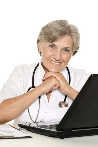 Пожилая женщина врач сидит с ноутбуком на белом — стоковое фото