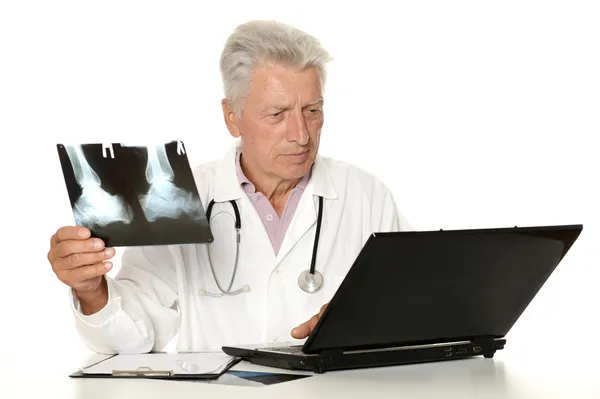 Alter Arzt sucht Röntgenbilder auf weißem Hintergrund — Stockfoto