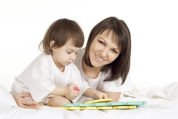 Hermosa mamá caucásica y su hija tumbada en la cama con un libro — Foto de Stock