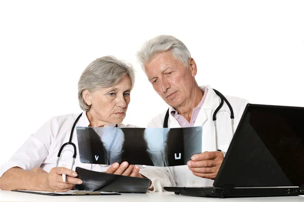 Médicos ancianos con una computadora portátil mirando rayos X en un blanco — Foto de Stock