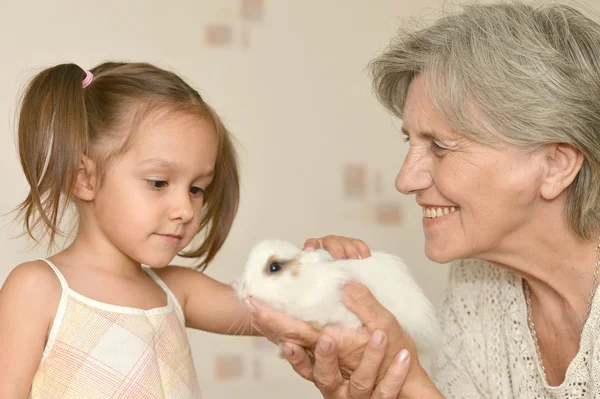 Mutlu yaşlı kadın ve genç bir kız ile bir küçük tavşan — Stok fotoğraf
