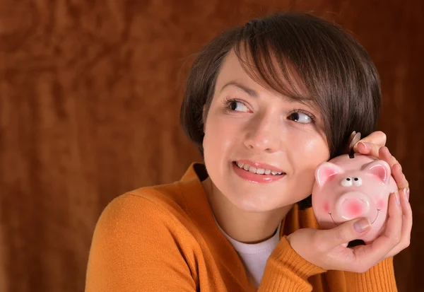 Menina com um porquinho banco em um marrom — Fotografia de Stock