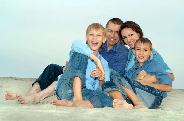 Familia feliz sentada en la arena — Foto de Stock