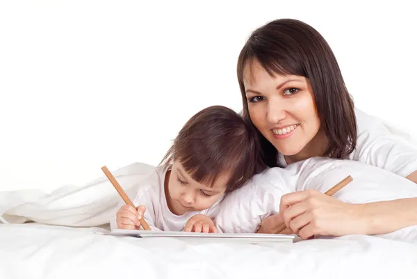 Een mooie Kaukasische moeder met haar dochter lyingwith een penci — Stockfoto