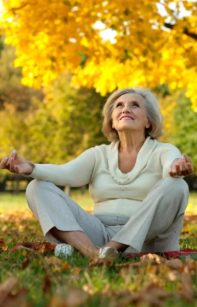 Anciana sentada en el parque de otoño — Foto de Stock