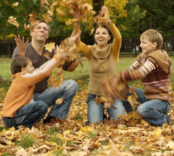 Hermosa familia tirar hojas de otoño — Foto de Stock