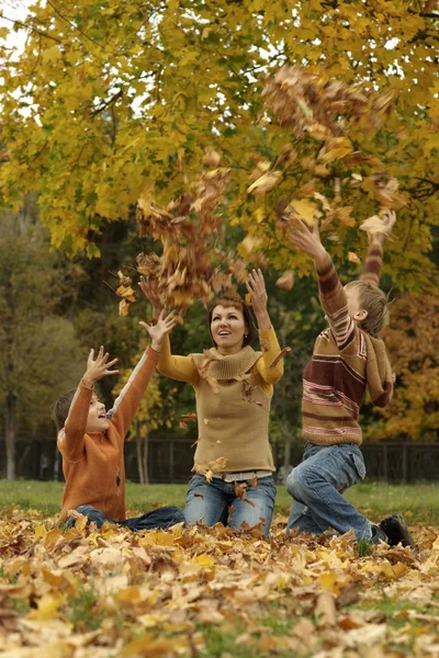 Madre e bambini gettando foglie autunnali — Foto Stock