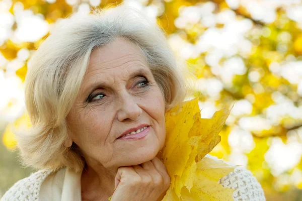 Frau steht auf einem Hintergrund aus gelben Blättern — Stockfoto