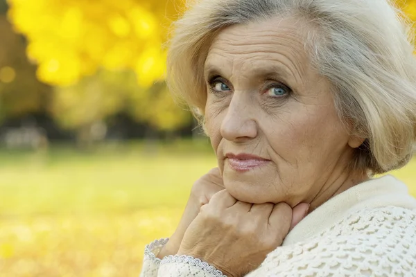 Vrouw staat op een achtergrond van gele bladeren — Stockfoto