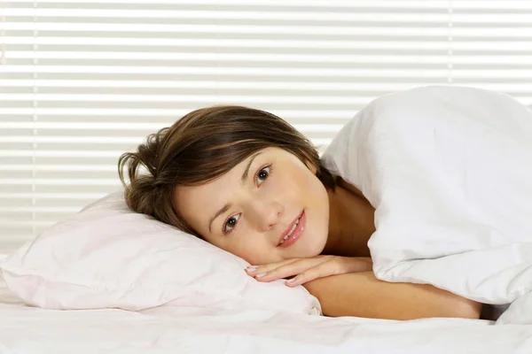 Portret szczęśliwej dziewczyny leżącej w łóżku — Zdjęcie stockowe