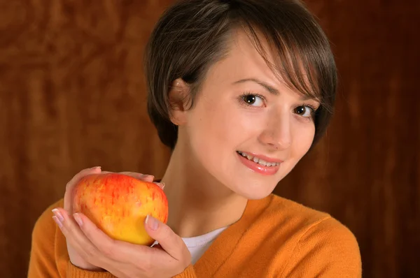 Flicka med ett äpple på en brun — Stockfoto