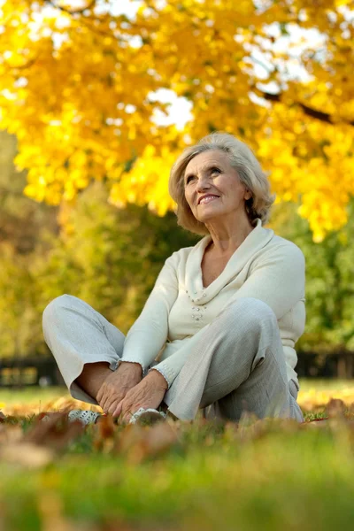 秋の公園で座っている素敵な歳の女性 — ストック写真