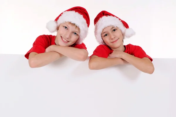 Kinder in Weihnachtsmützen mit Brett — Stockfoto