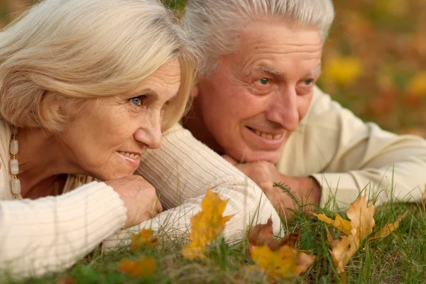 Old couple lying at autumn park — Stock Photo, Image