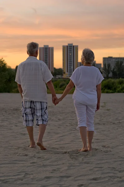 Elderly couple at sunset on a beach — Stock Photo, Image