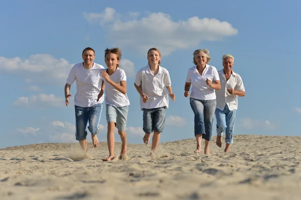 Familia feliz corriendo en una playa — Foto de Stock