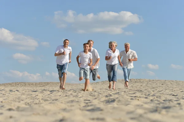 Familia feliz corriendo en una playa — Foto de Stock