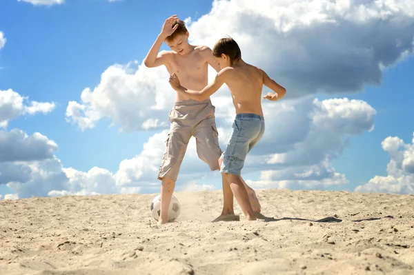 Två pojkar som spelar fotboll på en sand — Stockfoto